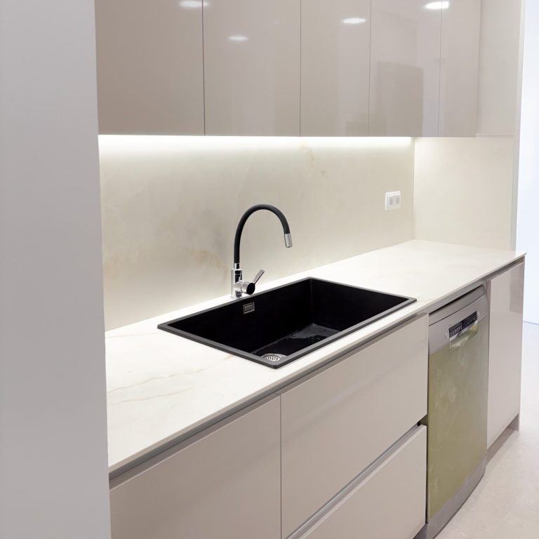 Cocina moderna con encimera blanca, fogones negros y grifería de cobre.