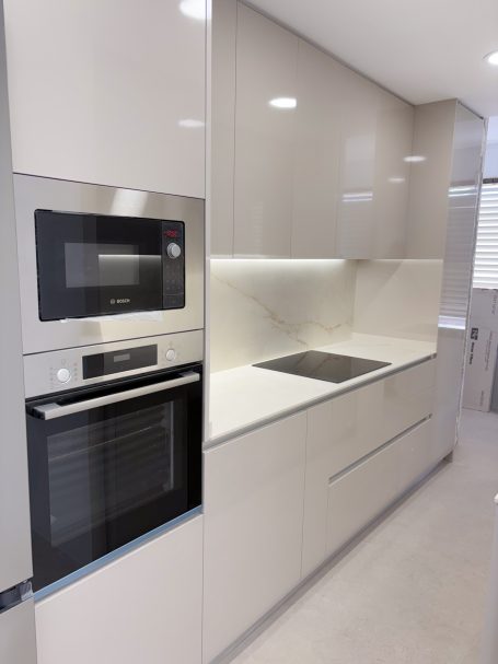 Cocina moderna con armarios de color claro, horno y microondas integrados.