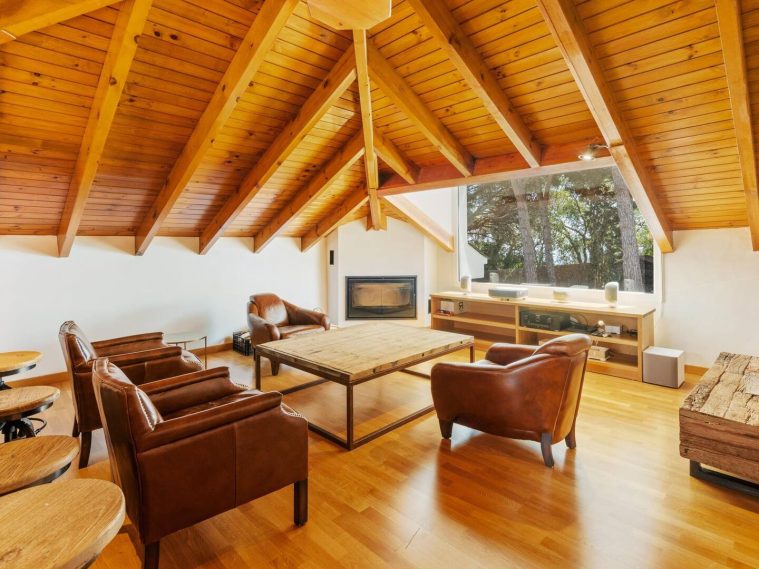 Salón acogedor con techo de madera, chimenea y mobiliario cómodo.