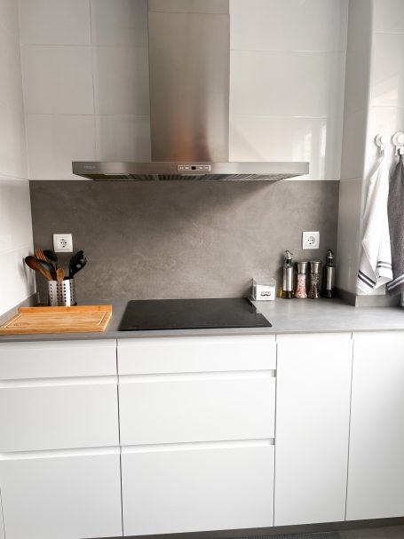 Cocina moderna con extractor, encimera negra y utensilios en un frutero de madera.