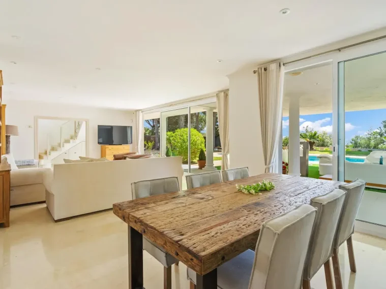 Interior de una casa moderna con comedor, sala de estar y vista al jardín.