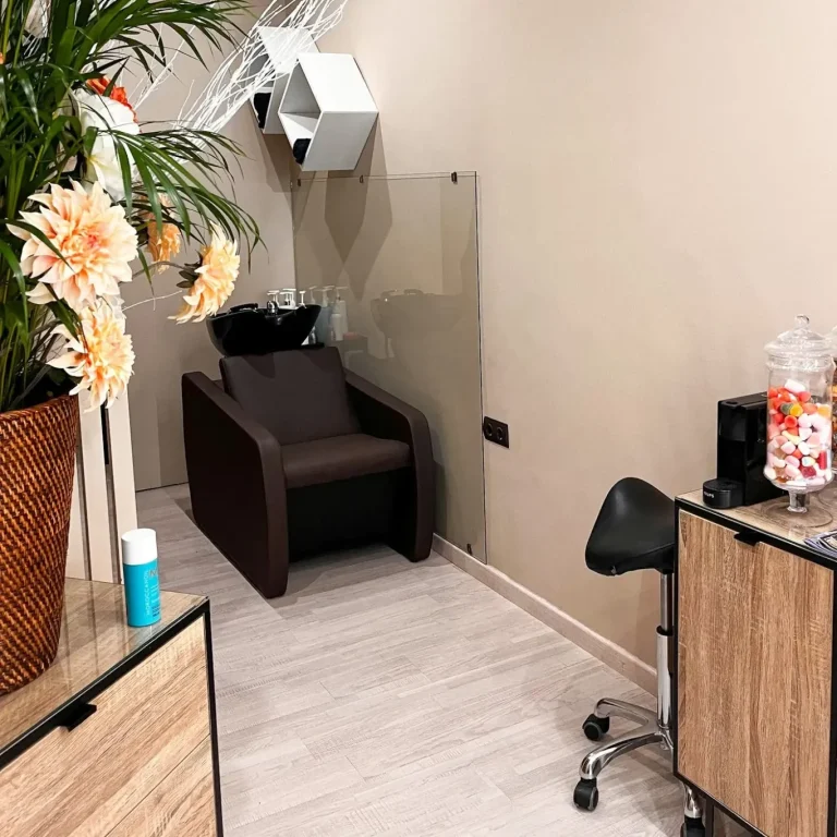 Sala de belleza con sillón, lavabo y mobiliario moderno. Decoración de plantas.