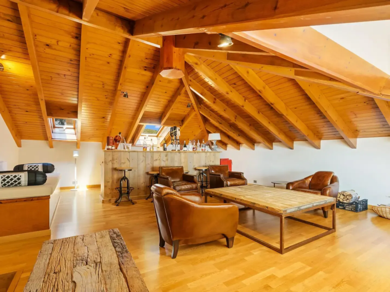 Sala de estar con techos altos de madera y muebles de cuero. Espacio acogedor y moderno.