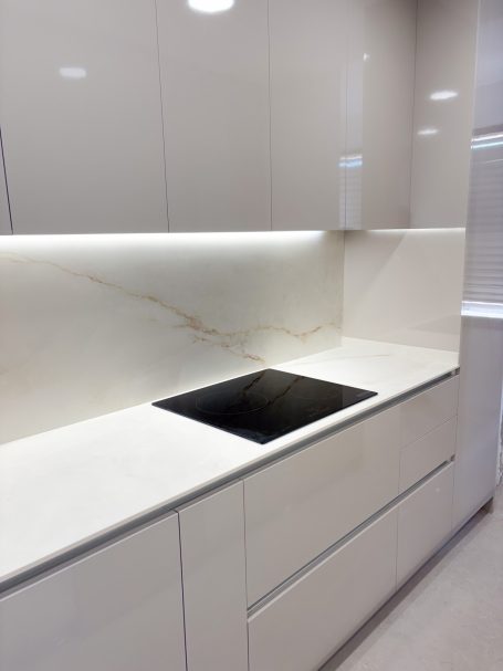 Cocina moderna con encimera clara y vitrocerámica negra, iluminación suave.